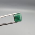 "Natural Emerald Panna Zamrud gemstone 4.39 carat octagon emerald cut from Zambia held in tweezers showing deep green color and natural jardin inclusions"