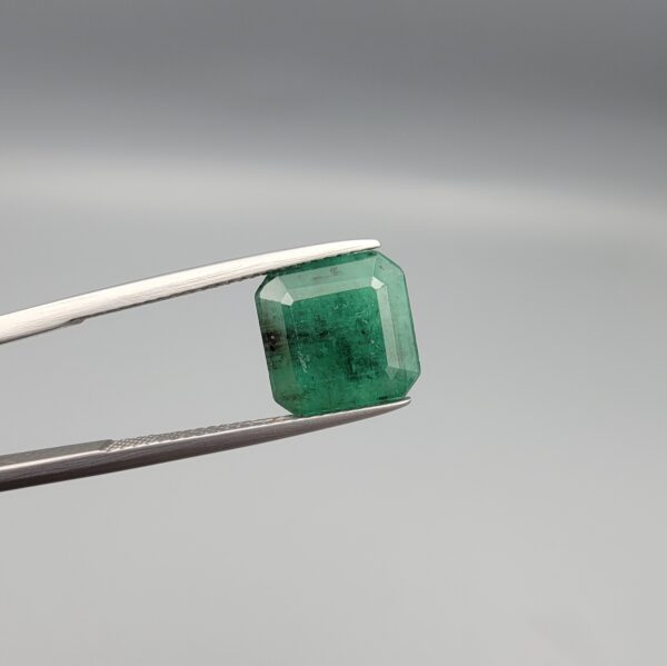 "Natural Emerald Panna Zamrud gemstone 4.39 carat octagon emerald cut from Zambia held in tweezers showing deep green color and natural jardin inclusions"