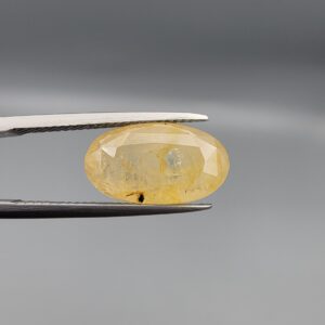 "Natural unheated Yellow Sapphire Pukhraj gemstone 10.60 carat large oval cut from Sri Lanka Ceylon held in tweezers showing golden color and visible natural fractures"