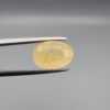 "Natural unheated Yellow Sapphire Pukhraj gemstone 6.37 carat large oval cut from Sri Lanka Ceylon held in tweezers showing pale golden color and natural feather inclusions"