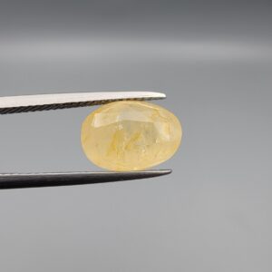 "Natural unheated Yellow Sapphire Pukhraj gemstone 6.37 carat large oval cut from Sri Lanka Ceylon held in tweezers showing pale golden color and natural feather inclusions"