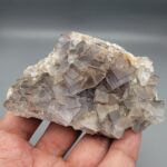 "Natural Fluorite crystal cluster specimen 1313 grams from Balochistan Pakistan showing large cubic purplish gray crystals with yellow limonite staining, held in hand"