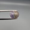 ​A precision-faceted 5.36-carat oval natural Ametrine gemstone held in tweezers against a gray backdrop, displaying a sharp half-and-half color partition of purple amethyst and golden-amber citrine with brilliant clarity.