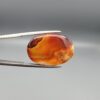 "Natural Carnelian Banded Agate Sulemani Aqeeq gemstone 32.29 carat oval cabochon from Yemen held in tweezers showing red, orange, yellow, and white natural color bands"