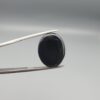 An 18.16-carat oval natural Yemeni agate cabochon held in tweezers against a gray backdrop. The front side shows an ice-white crystalline plume pattern framed by a dark border, while the reverse face is completely solid jet black.