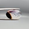 A rare 13.15 carat oval cabochon of natural Sulemani Aqeeq from Iran, pairing a classic black-and-orange banded edge with a sparkling druzy quartz crystal window flushed with deep maroon inclusions — a true collector's specimen that stands apart from typical solid black Sulemani stones.