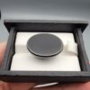 ​A 33.48-carat oval natural Iranian chalcedony agate cabochon displayed in a black presentation box. The high dome features translucent milky agate with multi-colored dendritic inclusions, mossy specks, and geode crystal pocket formations, backed by a seamless, shining jet-black base.
