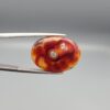"Natural Irani Fire Agate Sulemani Aqeeq gemstone 16.65 carat oval cabochon from Iran held in tweezers showing deep red and orange color with natural cavity eye inclusions and green moss spots"