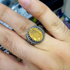 Hand-worn view of a men's Turkish design 925 sterling silver ring featuring a large 4 carat plus oval yellow-orange natural Ethiopian opal gemstone with intricate side band filigree.