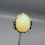 Studio photograph of a handcrafted men's 925 sterling silver ring featuring a massive 8+ carat natural faceted Ethiopian opal center stone with intricate vintage Turkish scrollwork on the shoulders.
