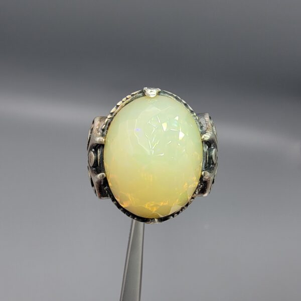 Studio photograph of a handcrafted men's 925 sterling silver ring featuring a massive 8+ carat natural faceted Ethiopian opal center stone with intricate vintage Turkish scrollwork on the shoulders.