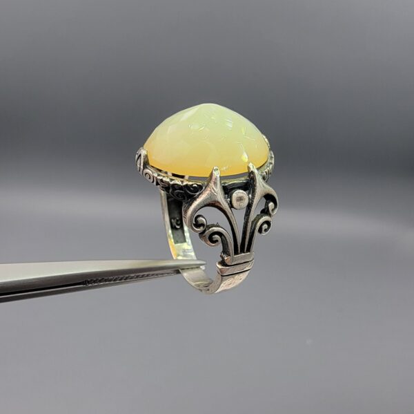 Studio photograph of a handcrafted men's 925 sterling silver ring featuring a massive 8+ carat natural faceted Ethiopian opal center stone with intricate vintage Turkish scrollwork on the shoulders.
