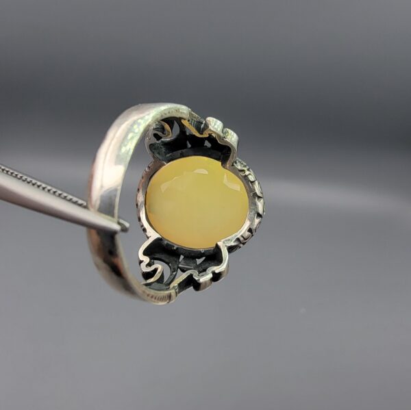 Studio photograph of a handcrafted men's 925 sterling silver ring featuring a massive 8+ carat natural faceted Ethiopian opal center stone with intricate vintage Turkish scrollwork on the shoulders.