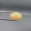 Studio photograph held in steel tweezers showcasing a massive 10.67 carat natural oval-shaped Ethiopian opal loose gemstone featuring a double-side fancy cut with flat and domed facets.
