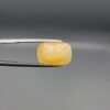 Studio photograph held in steel tweezers showcasing a large 13.70 carat natural cushion-shaped yellow sapphire (Pukhraj) loose gemstone with vibrant golden-yellow hue.