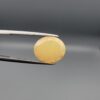 Studio photograph held in steel tweezers showcasing a 4.05 carat natural oval-shaped Ethiopian opal loose gemstone featuring a double-side fancy cut with flat and domed facets.