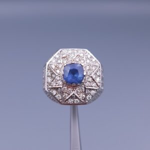 Studio close-up photograph of a handcrafted 925 sterling silver men's ring featuring a central 2+ carat blue sapphire surrounded by a geometric star design pavé-set with natural diamonds.