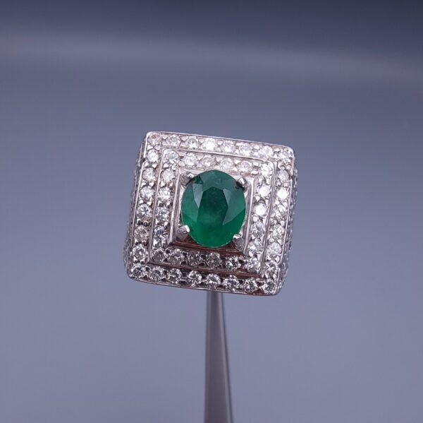 Studio close-up photograph of a handcrafted size 23 men's 925 sterling silver ring centered with a 1.60 carat oval emerald framed by a double rectangular tier of pavé-set natural diamonds.