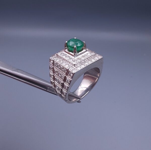 Studio close-up photograph of a handcrafted size 23 men's 925 sterling silver ring centered with a 1.60 carat oval emerald framed by a double rectangular tier of pavé-set natural diamonds.