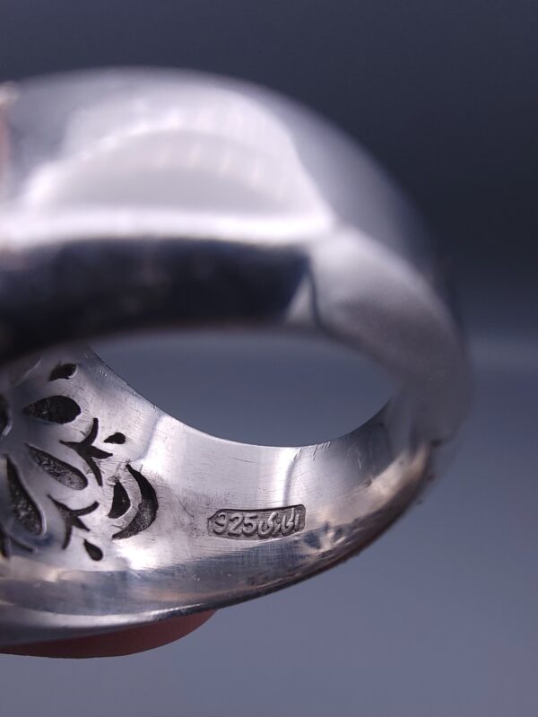 Studio close-up photograph of a handcrafted 925 sterling silver men's ring featuring a central 2+ carat blue sapphire surrounded by a geometric star design pavé-set with natural diamonds.