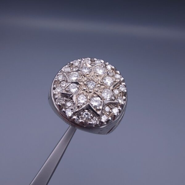 Studio close-up photograph of a handcrafted size 17 men's 925 sterling silver cluster ring featuring a circular face with a geometric star design completely pavé-set with sparkling natural diamonds.