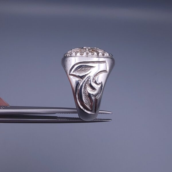Studio close-up photograph of a handcrafted size 17 men's 925 sterling silver cluster ring featuring a circular face with a geometric star design completely pavé-set with sparkling natural diamonds.