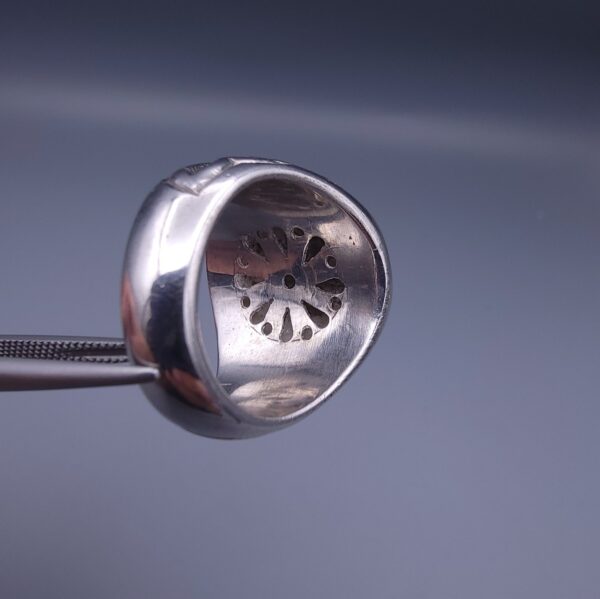 Studio close-up photograph of a handcrafted size 17 men's 925 sterling silver cluster ring featuring a circular face with a geometric star design completely pavé-set with sparkling natural diamonds.