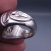 Studio close-up photograph of a handcrafted size 17 men's 925 sterling silver cluster ring featuring a circular face with a geometric star design completely pavé-set with sparkling natural diamonds.