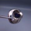 Studio close-up photograph of a handcrafted men's 925 sterling silver ring featuring a massive 19.72 carat oval blue sapphire center stone surrounded by a zircon halo and detailed with seven carved wheel motifs along the shank.