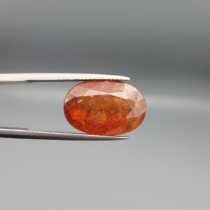 Studio close-up photographs showing the front and back view of a 10.74 carat oval-cut natural hessonite garnet gemstone displaying a warm honey-orange color and semi-transparent clarity.