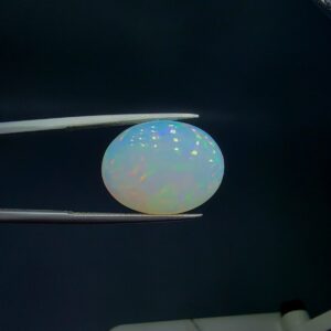 Studio close-up photograph of an 8.48 carat oval cabochon natural Ethiopian Welo opal showcasing a vibrant green, red, and yellow play-of-color against a dark background.