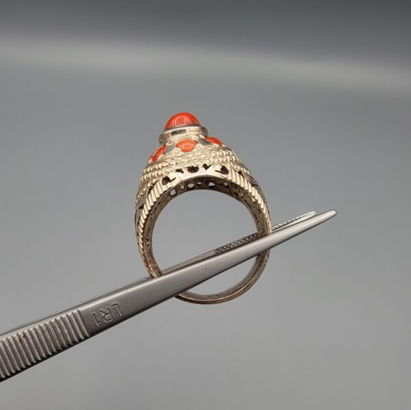 Studio close-up photographs showing the top and side profile views of a handcrafted 925 sterling silver ring featuring a natural Italian coral center stone and matching coral side accents.