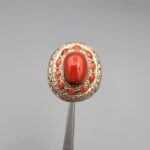 Studio close-up photographs showing the top and side profile views of a handcrafted size 22 solid 925 sterling silver ring featuring a natural Italian coral center stone and matching coral side accents.