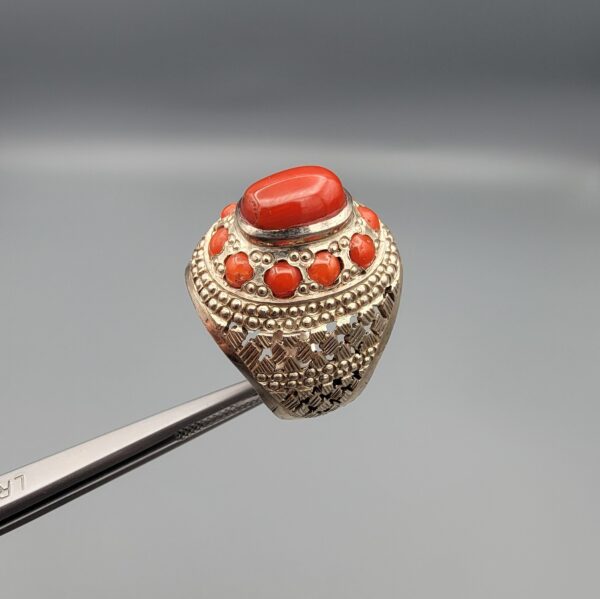 Studio close-up photographs showing the top and side profile views of a handcrafted size 22 solid 925 sterling silver ring featuring a natural Italian coral center stone and matching coral side accents.