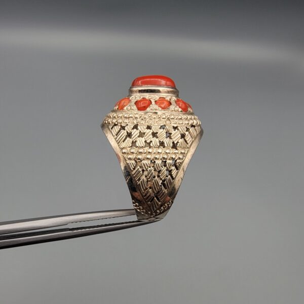 Studio close-up photographs showing the top and side profile views of a handcrafted size 22 solid 925 sterling silver ring featuring a natural Italian coral center stone and matching coral side accents.