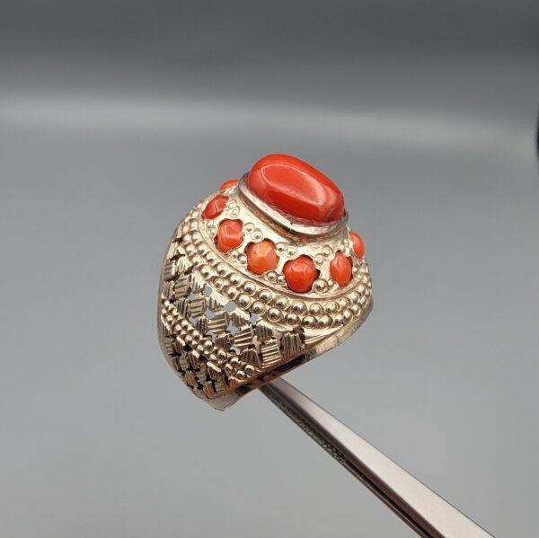 Studio close-up photographs showing the top and side profile views of a handcrafted size 22 solid 925 sterling silver ring featuring a natural Italian coral center stone and matching coral side accents.