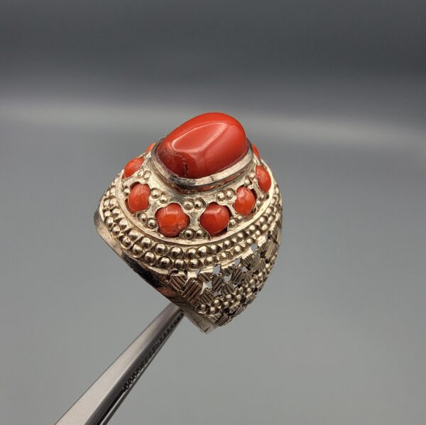 Studio close-up photographs showing the top and side profile views of a handcrafted size 22 solid 925 sterling silver ring featuring a natural Italian coral center stone and matching coral side accents.