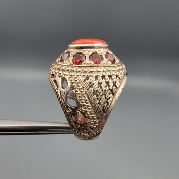 Studio close-up photographs showing the top and side profile views of a handcrafted size 23 solid 925 sterling silver ring featuring a natural Italian coral center stone surrounded by faceted garnet accent stones.