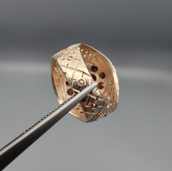 Studio close-up photographs showing the top and side profile views of a handcrafted size 23 solid 925 sterling silver ring featuring a natural Italian coral center stone surrounded by faceted garnet accent stones.