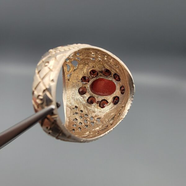 Studio close-up photographs showing the top and side profile views of a handcrafted size 23 solid 925 sterling silver ring featuring a natural Italian coral center stone surrounded by faceted garnet accent stones.