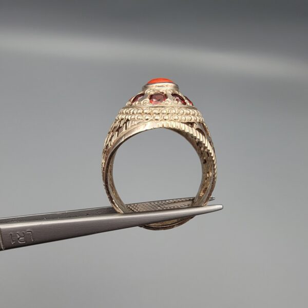 Studio close-up photographs showing the top and side profile views of a handcrafted size 23 solid 925 sterling silver ring featuring a natural Italian coral center stone surrounded by faceted garnet accent stones.