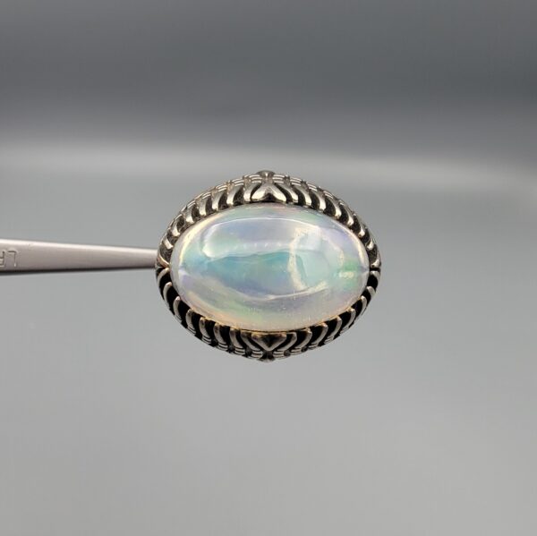 Studio close-up photographs showing the top and detailed side shank views of a 10+ carat natural Ethiopian opal ring crafted in solid sterling silver with an intricate Turkish design.
