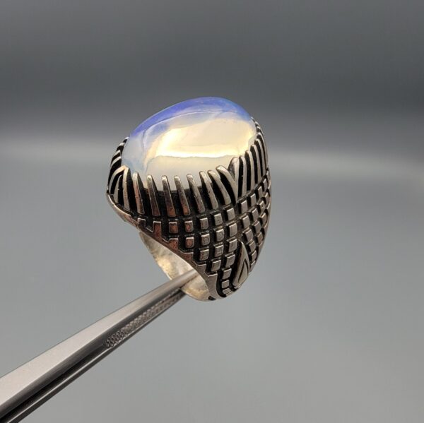 Studio close-up photographs showing the top and detailed side shank views of a 10+ carat natural Ethiopian opal ring crafted in solid sterling silver with an intricate Turkish design.