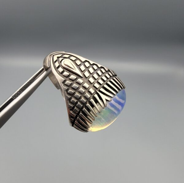 Studio close-up photographs showing the top and detailed side shank views of a 10+ carat natural Ethiopian opal ring crafted in solid sterling silver with an intricate Turkish design.