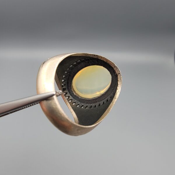 Studio close-up photographs showing the top and detailed side shank views of a 10+ carat natural Ethiopian opal ring crafted in solid sterling silver with an intricate Turkish design.