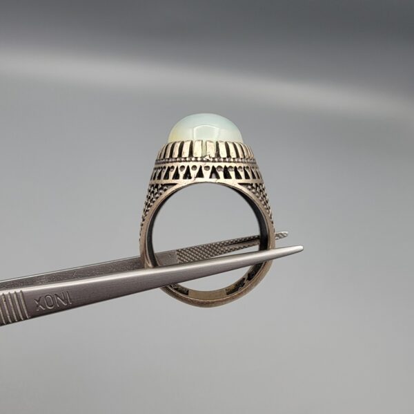 Studio close-up photographs showing the top and detailed side shank views of a 10+ carat natural Ethiopian opal ring crafted in solid sterling silver with an intricate Turkish design.