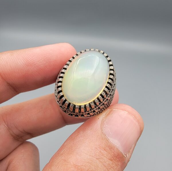 Studio close-up photographs showing the top and detailed side shank views of a 10+ carat natural Ethiopian opal ring crafted in solid sterling silver with an intricate Turkish design.