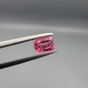 Studio close-up photographs showing the top and facet profile views of a 0.63 carat cushion mixed cut natural rubellite tourmaline loose gemstone held in tweezers.
