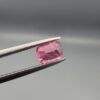 Studio close-up photographs showing the top and facet profile views of a 0.63 carat cushion mixed cut natural rubellite tourmaline loose gemstone held in tweezers.