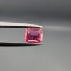 Studio close-up photographs showing the top and facet profile views of a 0.68 carat cushion mixed cut natural rubellite tourmaline loose gemstone held in precision tweezers.